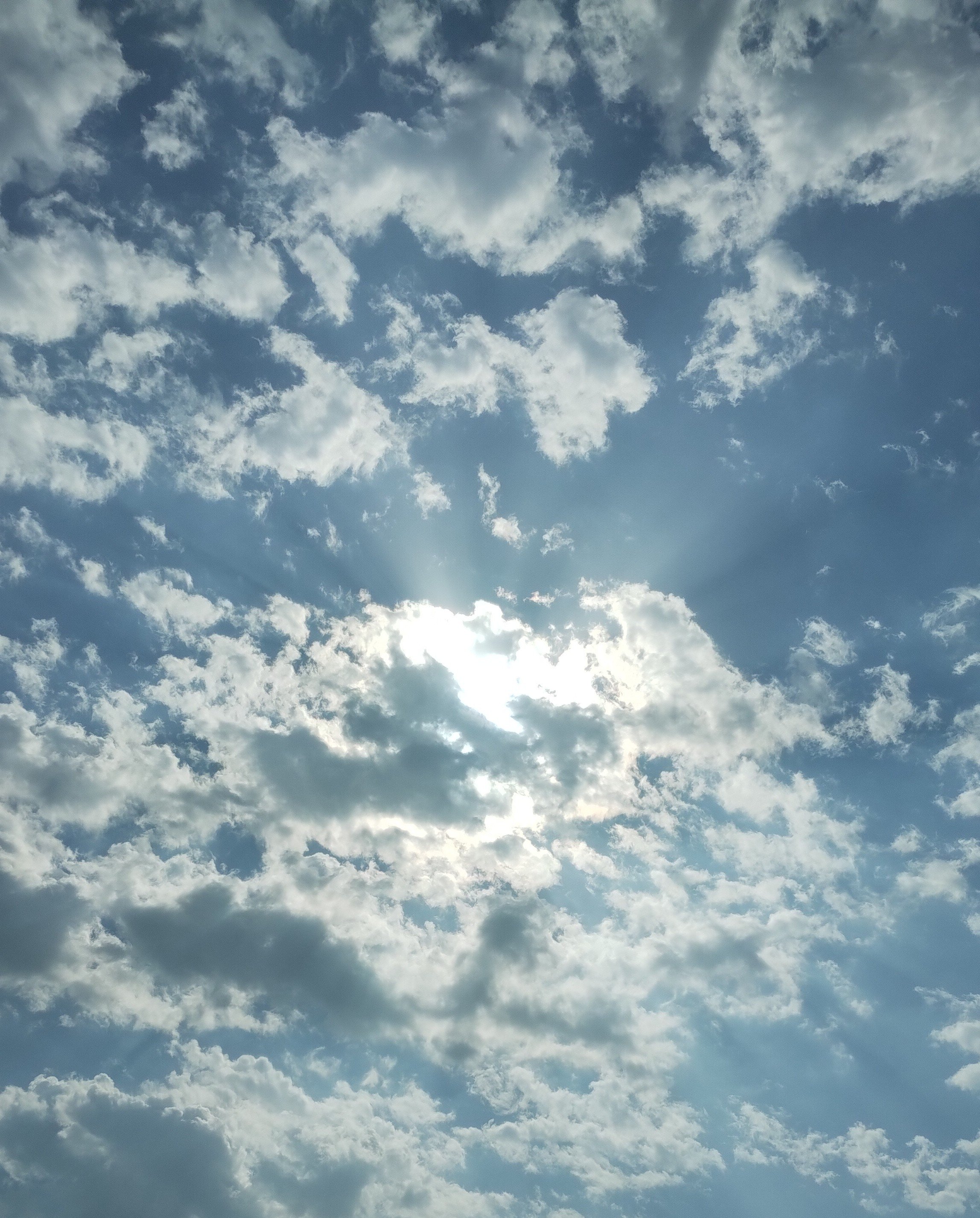 Photograph of the sky, with some sunlight peaking through the middle.