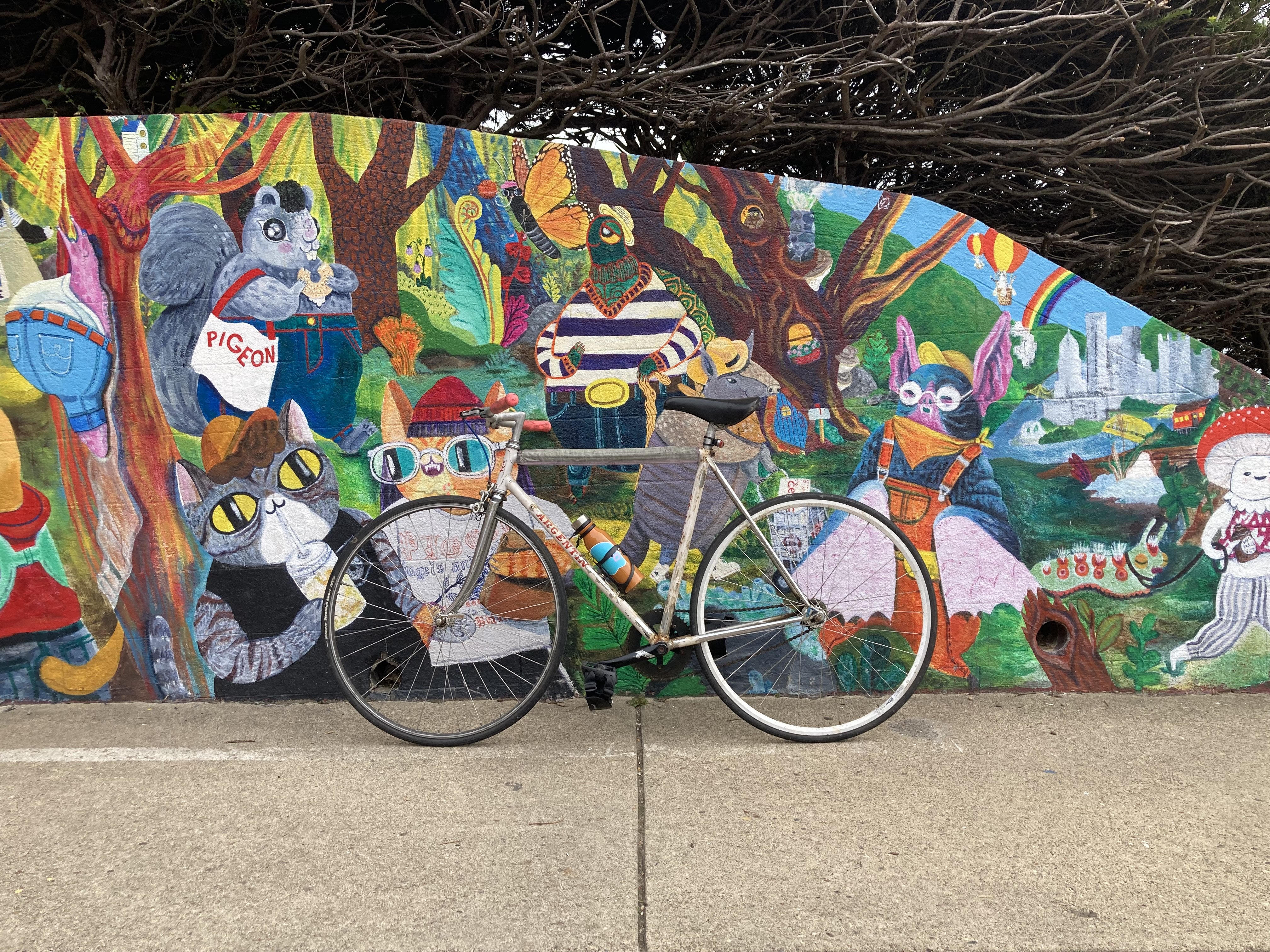 A fixed gear bicycle leaning against a colorful mural