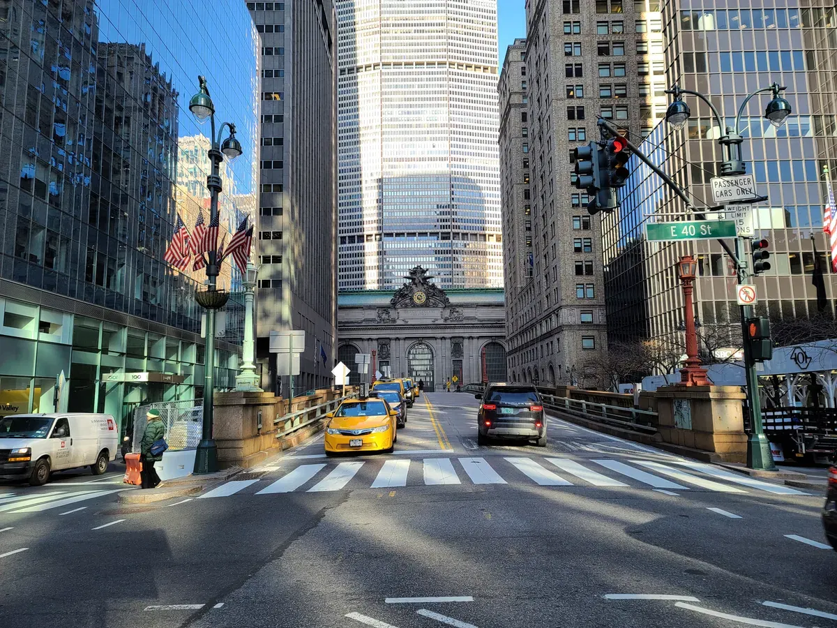 A wide angle on a city street leading to a clockface