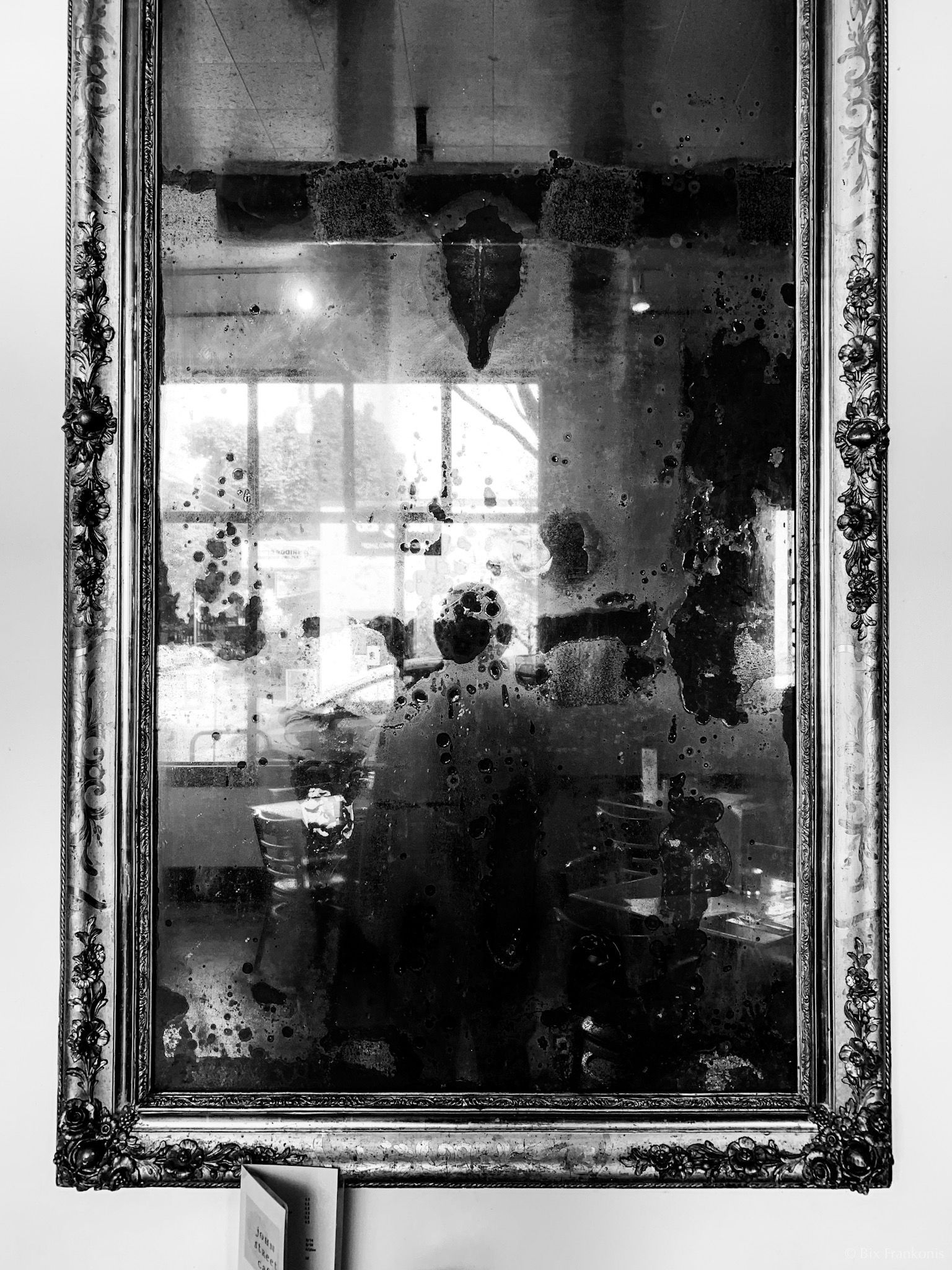 Black-and-white self-portrait in a splotchy mirror.