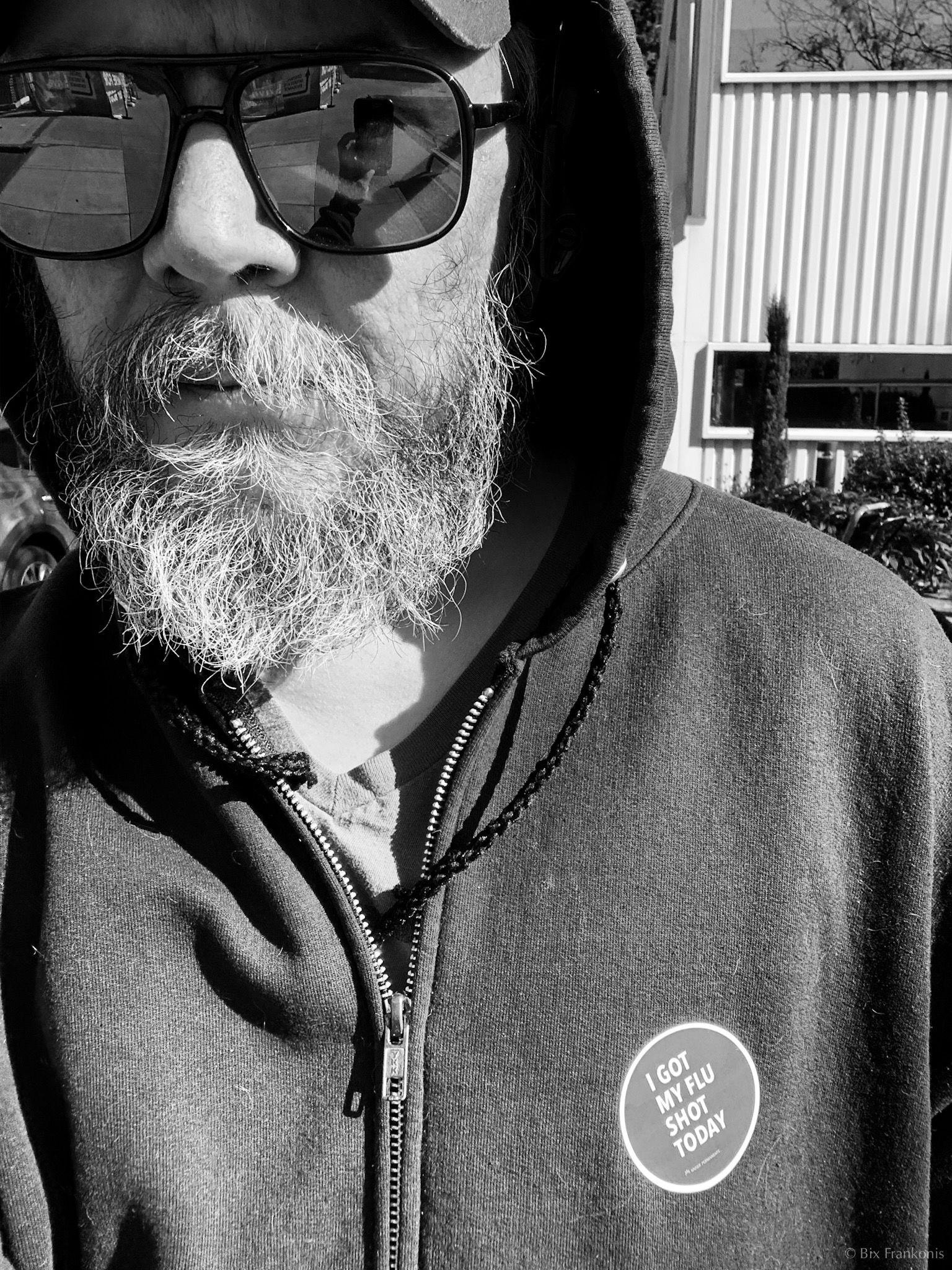 Selfie of bearded man in mirrorshades and hoodie with ‘I Got My Flu Shot Today’ sticker