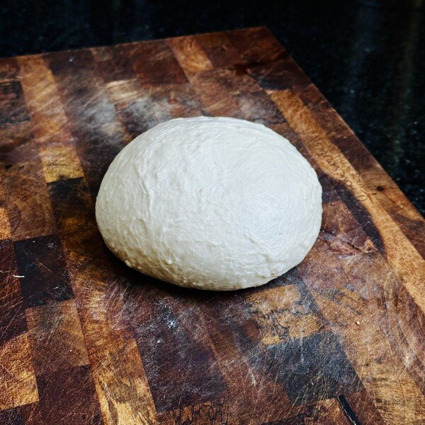 A ball of pizza dough on a cutting board