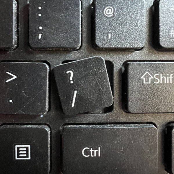 A keyboard. The slash/question mark key is out of its slot, turned slightly askew. 