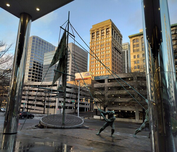 Sculpture and skyline framed by portico of office building 
