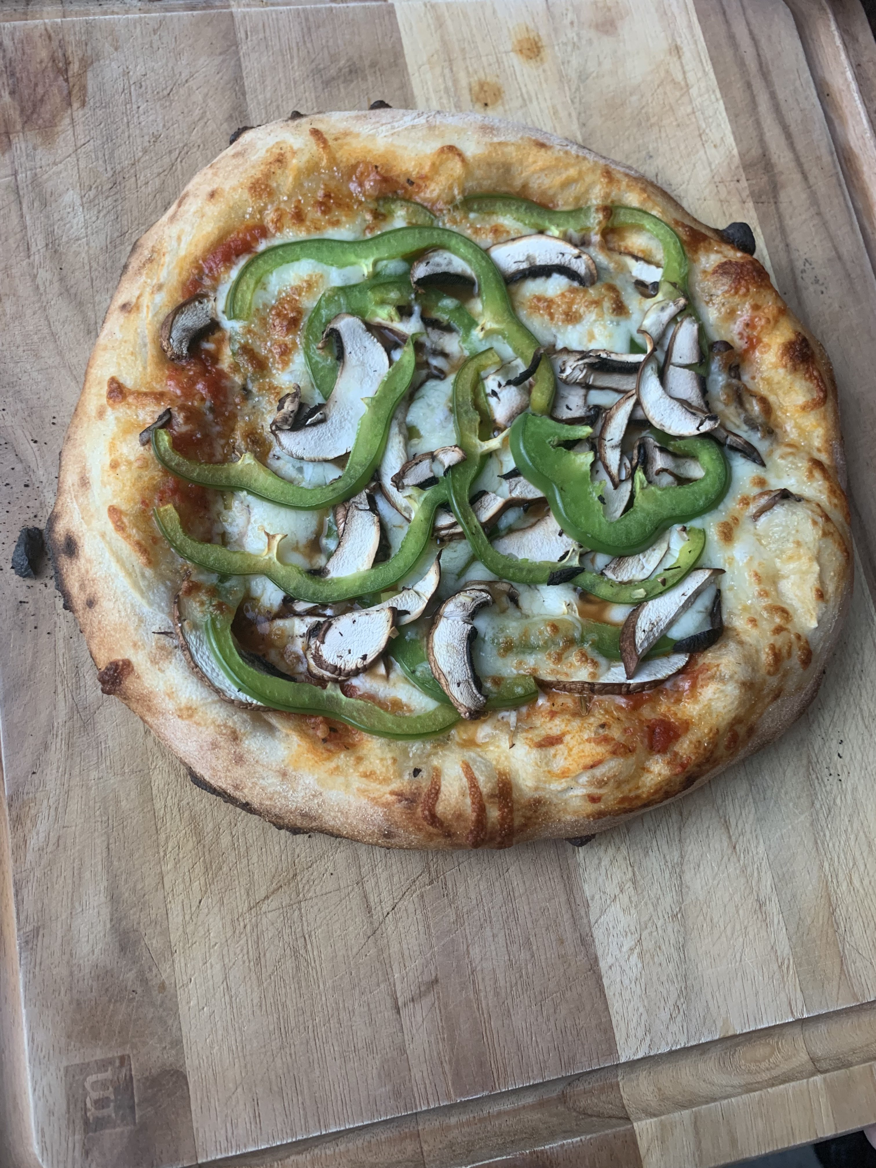 Homemade pizza, lots of green pepper and mushrooms visible,  'leopard spotting' on the crust    IT WAS DELICIOUS.