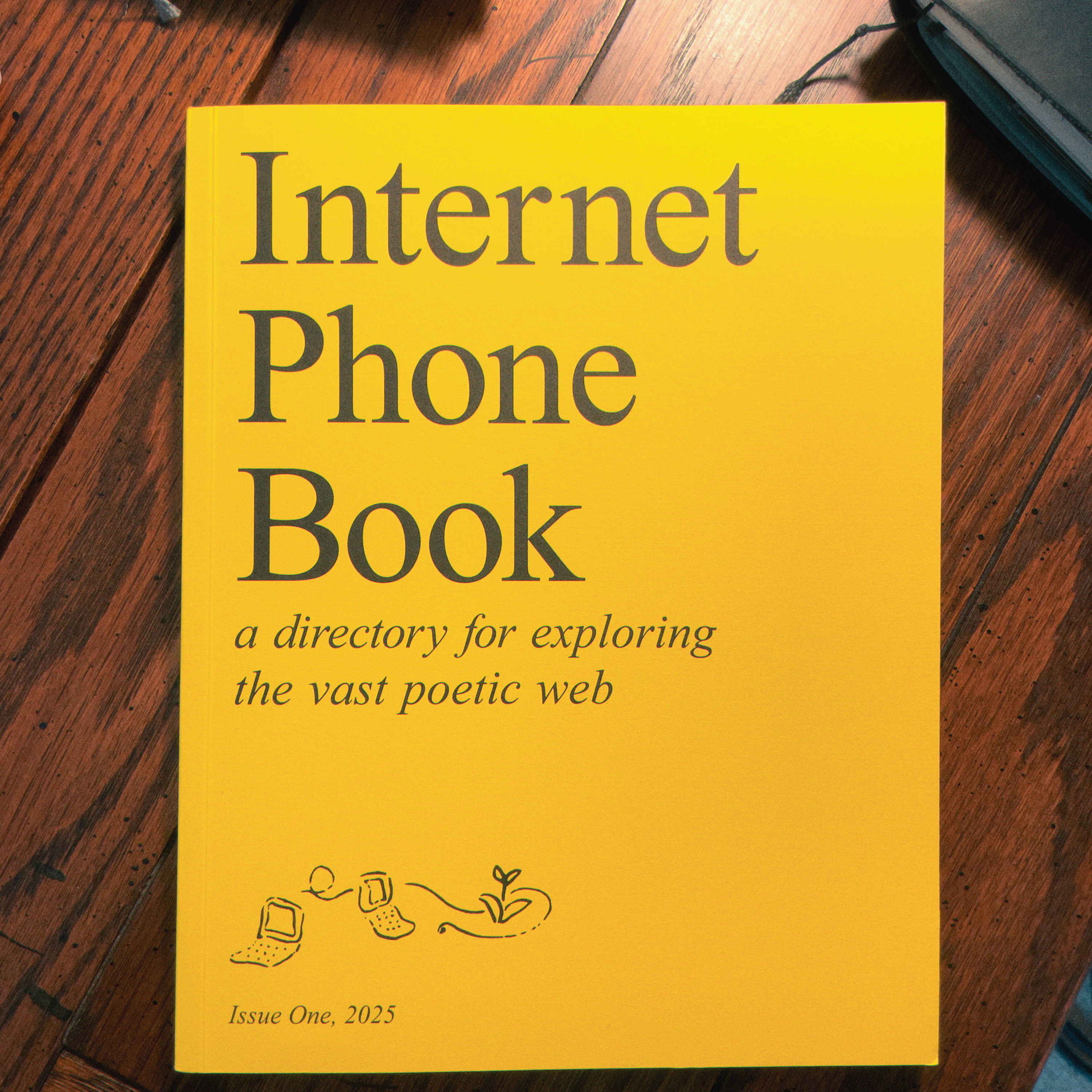 a top-down shot of a bright yellow book with black serif text reading "Internet Phone Book: a directory for exploring the vast poetic web" and "Issue One, 2025"