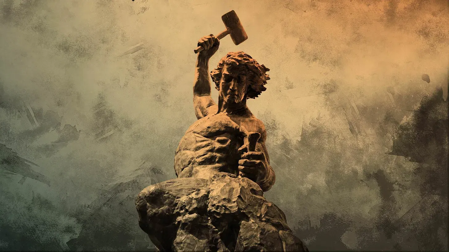 A statue holding a hammer and a chisel, appearing to be about to carve the rock that makes up his unfinished legs