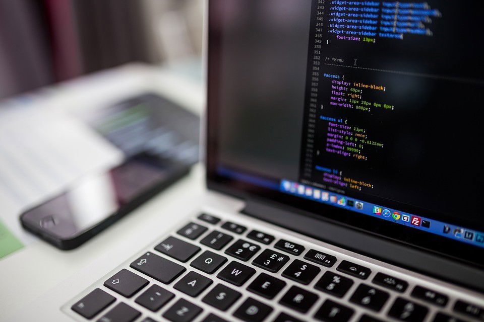 Stock image of a corner of a macbook with some code displayed. The code appears to be CSS, in case that matters.