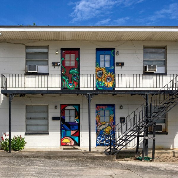 Colorfully painted doors on an otherwise plain apartment building.