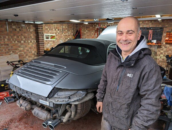 George's dad standing next to a Porsche.