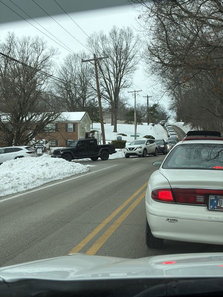Two hour delay drop off pile up

Snowy street with parked cars lining the street, bare trees, and houses under a gray sky. 