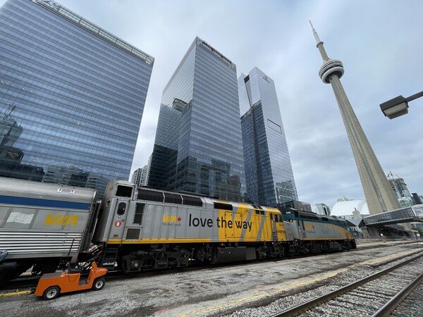 Two F40PH locomotives with some glass skyscrapers and the CN Tower in the background.