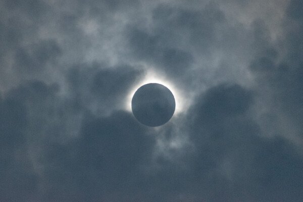 The sun during totality with grey clouds in front.