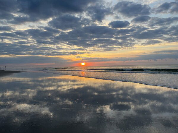 Sunrise over the surf at a North Carolina beach, with reflections of the clouds in the shallow water