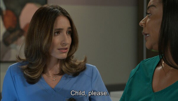 A close-up screenshot of two women from a television show. On the left, a white woman with long, light brown wavy hair and a worried expression is wearing light blue medical scrubs. She is looking to the right at a Black woman, who is partially visible on the right side of the frame wearing a green shirt. The subtitle reads, 'Child, please.' The mood is confrontational and slightly humorous.
