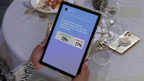 A tablet held over a dinner table showing an Instagram Story poll asking, 'If you had the chance to help a loved one reunite with their mom...would you? #chelschats.' The results are 73% for 'MIND YA BUSINESS, SIS' and 27% for 'REUNITE THEM.'