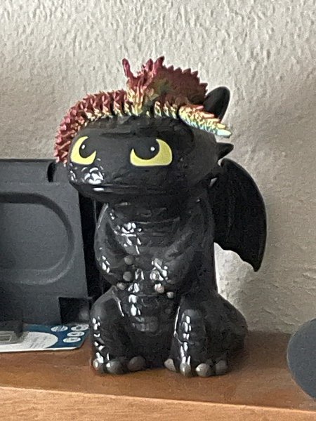 A ceramic toothless looking up at a rainbow 3d printed articulated dragon.