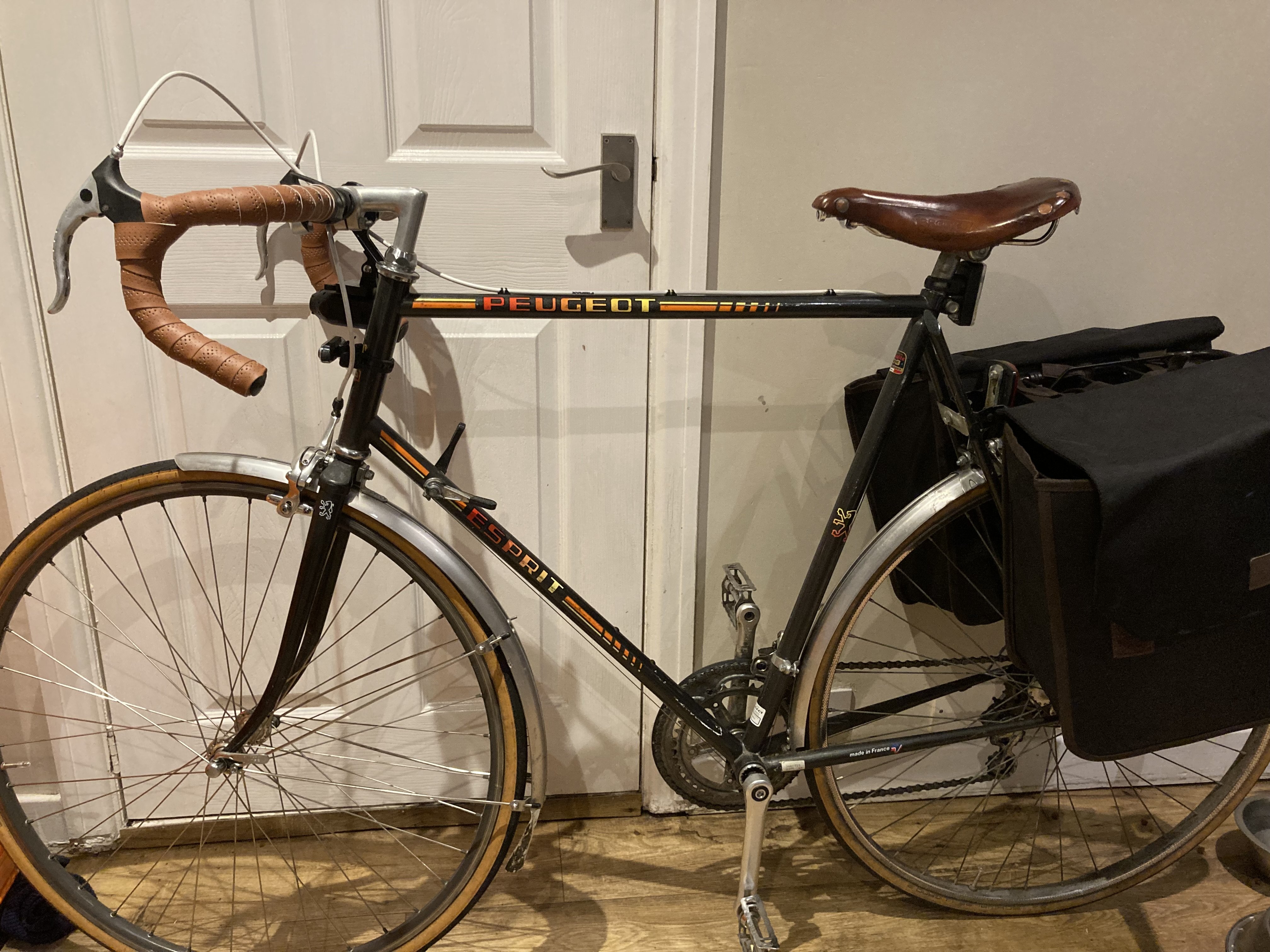 Vintage Peugeot bike, with fresh brown handlebar tape, a new leather saddle, and rear pannier bags