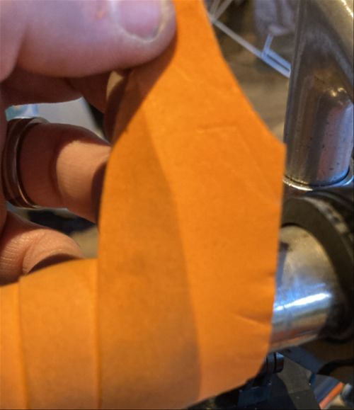 Handlebar tape with a line down the middle. One side is fresh, bright orange, the other is the same colour but stained with months of dirt