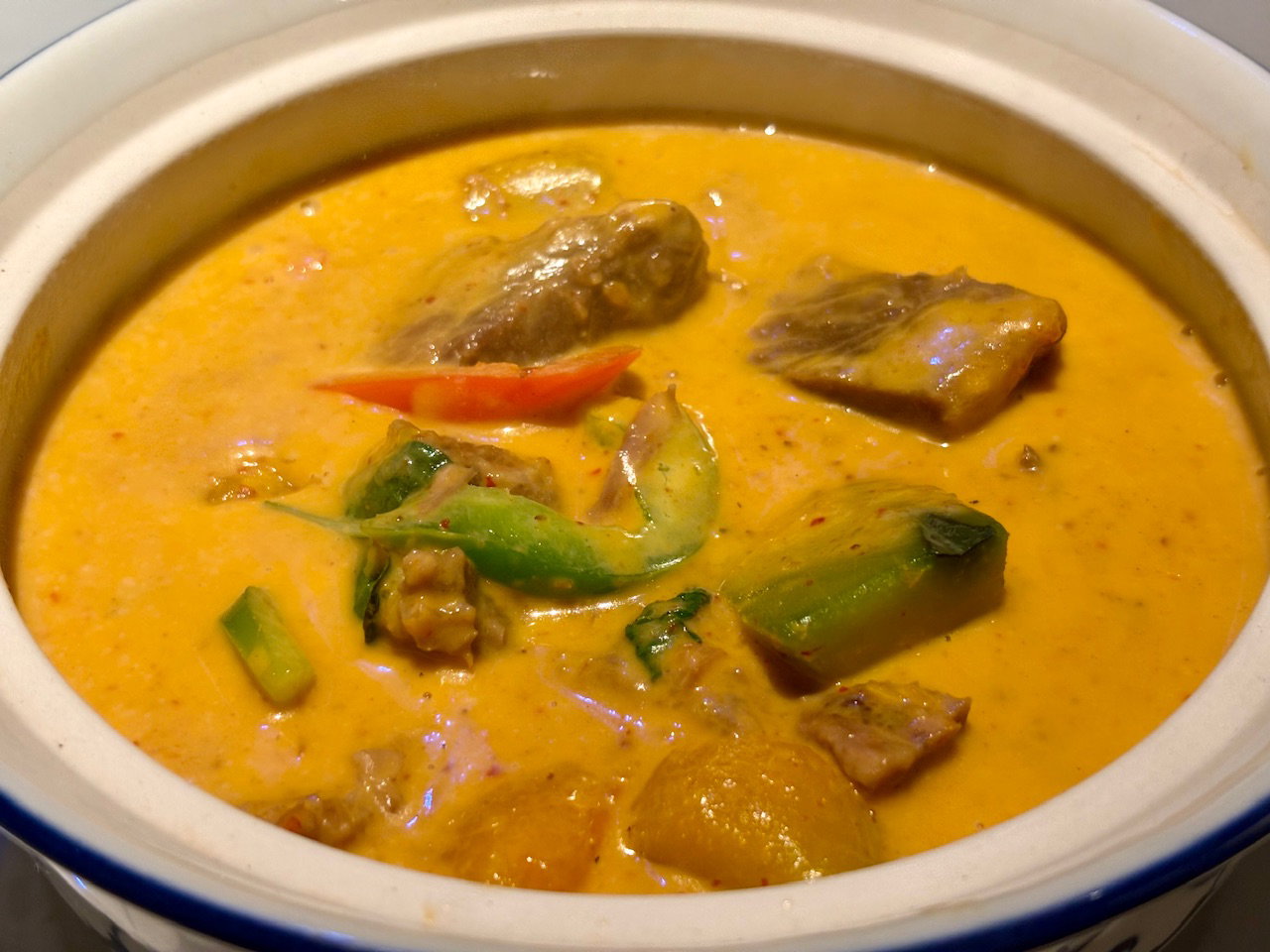 A bowl of slow roasted beef and bell peppers in a delicious orange panang curry sauce.