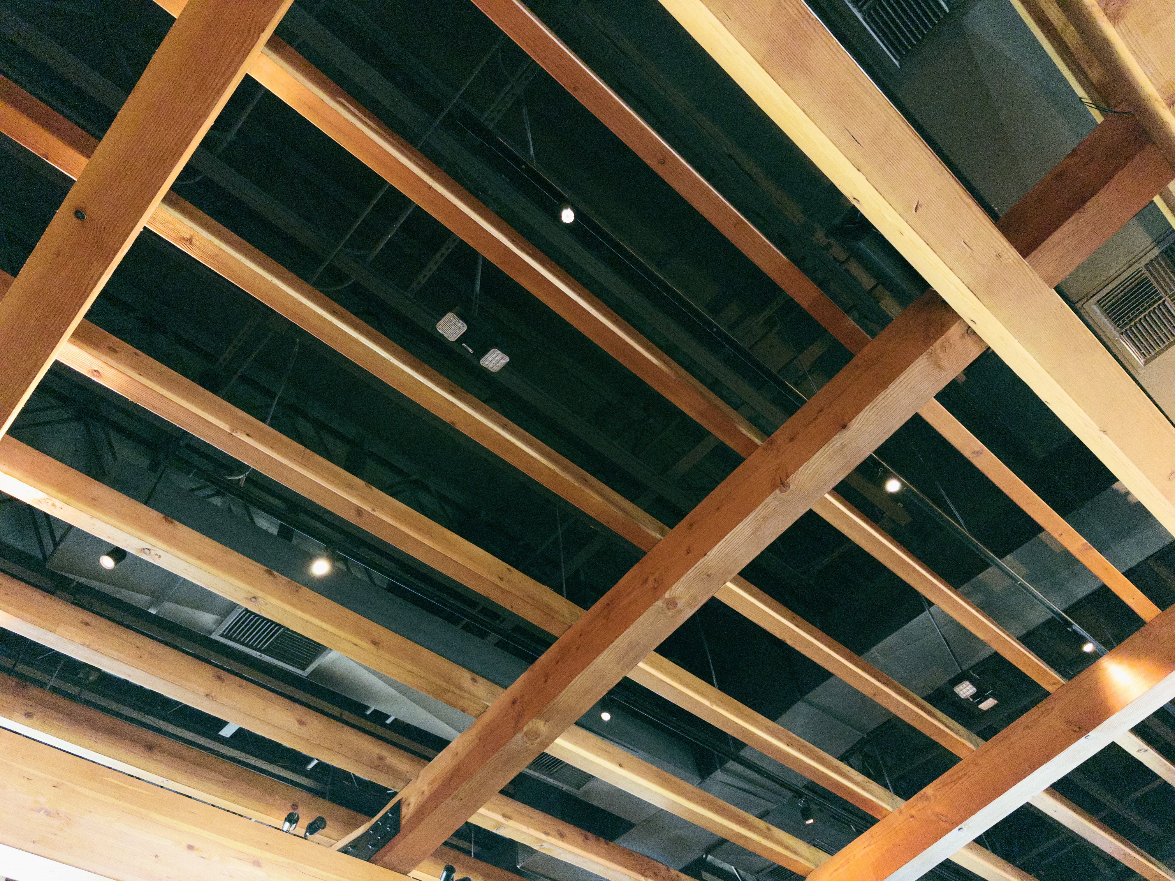 Wood beams cross diagonally below a black ceiling.