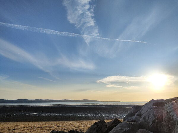 The sun is setting at the beach over a rising tide.