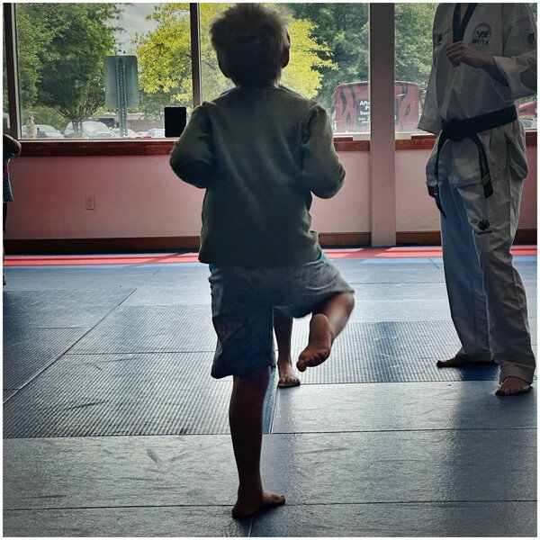My son stands ready with knee bent for a kick at a Taekwondo practice session. 