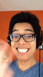 Miguel a masculine Filipino male with black hair and glasses is smiling and waving at the camera