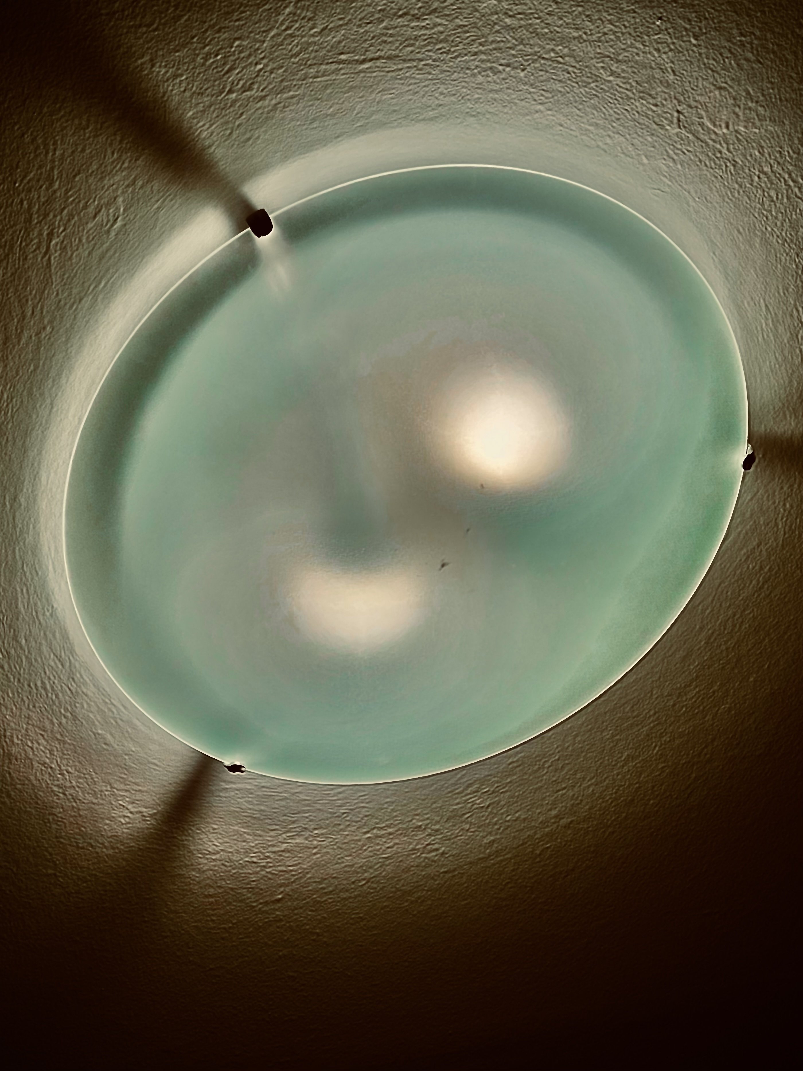 A ceiling light fixture with three shadows spreading from the points where the light is fixed to the ceiling. The 