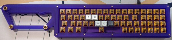 a purple keyboard, modeled as a machete, called the Mechete, with keycaps spelling out 'oh no!'