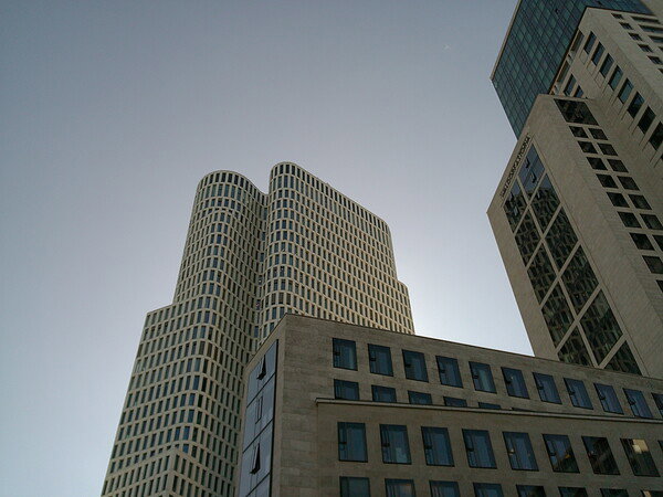 Cityscape with high-rise buildings, wavy cylindrical tower, and rectangular buildings.