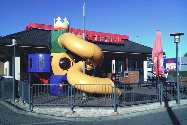Fast-food restaurant with play area, red signage, and clear blue sky