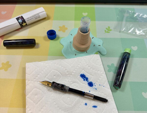 Behind the magic. Filling a fountain pen by dipping a converter into an ink vial, held in place by a melted ice cream 3D printed holder. As you do.