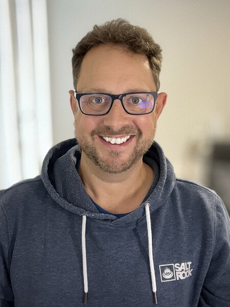 A profile picture of a white 40 something male. He’s smiling, wearing a hoodie and glasses. 