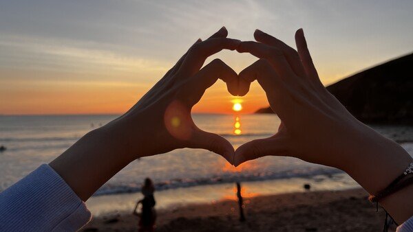 My daughter’s hands making a heart in front of an ocean view. The sun is glowing I  the centre of the heart. ❤️ 