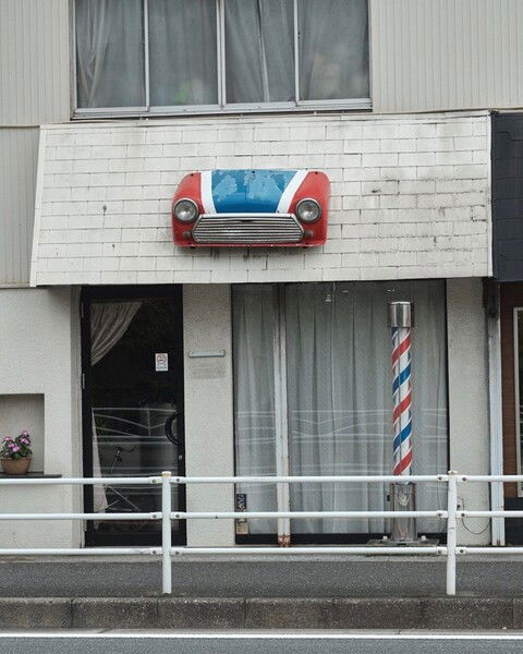 Red and blue car on a city building storefront.