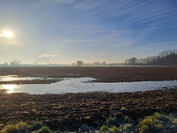 Koud landschap van bevroren water op een omgeploegd veld in de buurt van Duffel