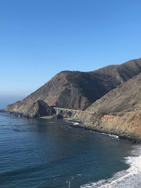 A picture of Big Sur, California, with the ocean, as well as one of the original bridges in view.