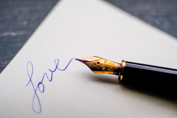 fountain pen and paper, with the word love written on it. - Photo by John Jennings on Unsplash