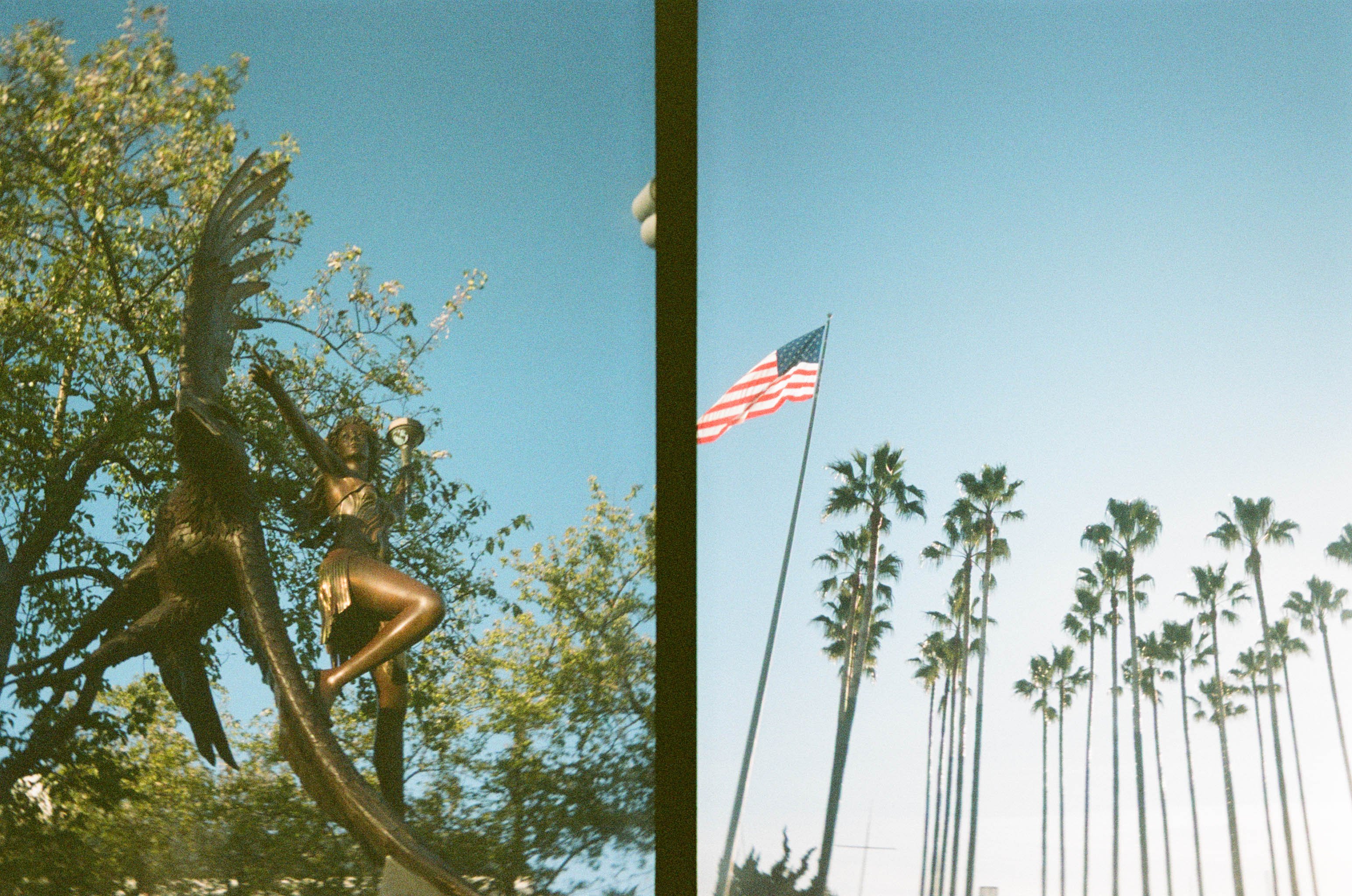 A 35mm film photo frame with two exposures. The first photo is a statue of a woman and an eagle flying beside her with a tree behind them. The second photo is an American flag flying with palm trees in the distance