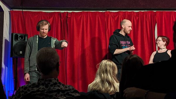 three people on stage playing an improv scene