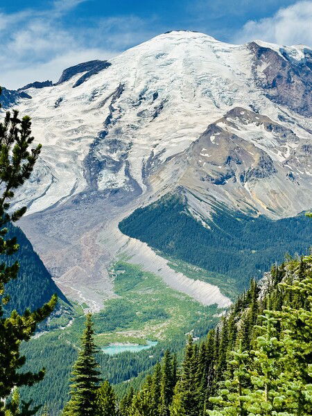 A view of snow capped Mt. Rainier and Emmons Glacier. A glacial lake can be seen in the valley below. 