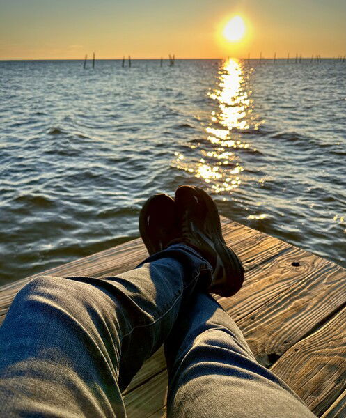 Sitting on a dock watching the sunset over the bay. 